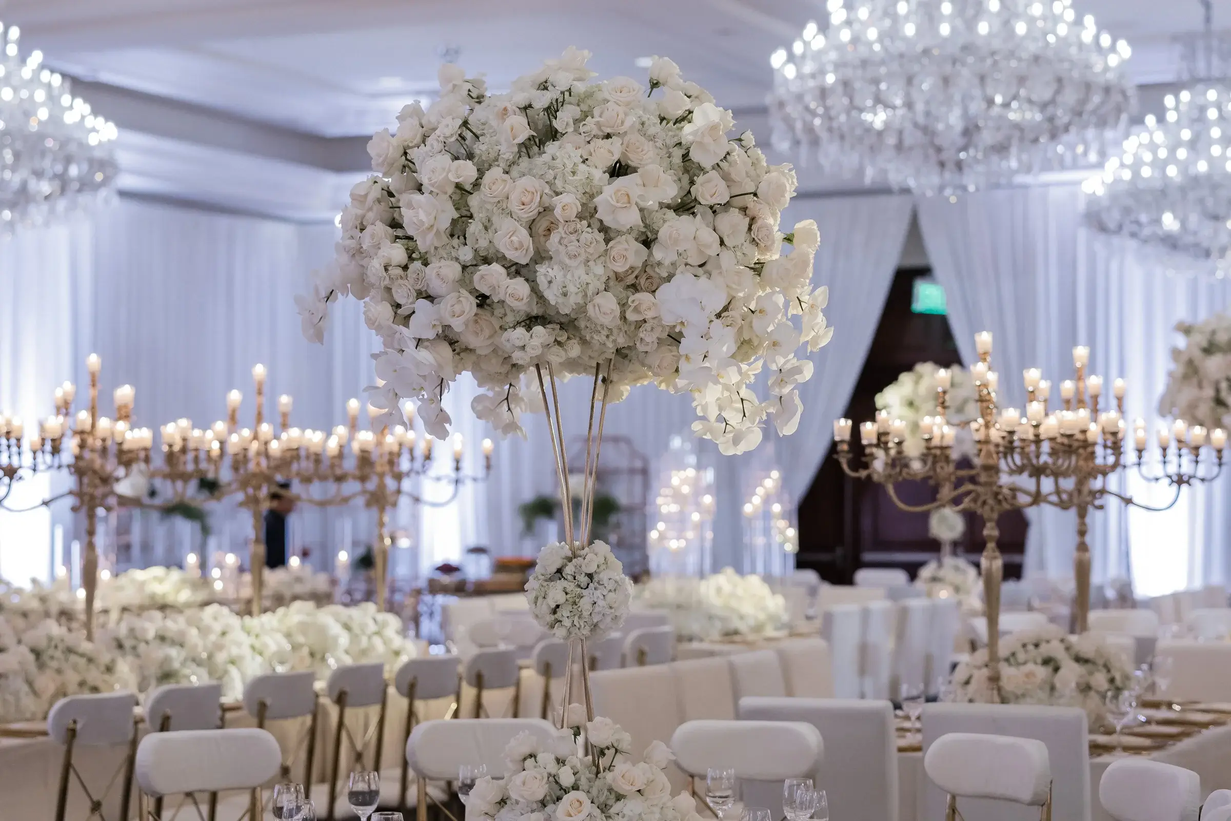 White rose and orchid centerpiece beneath crystal chandeliers at the Four Seasons Hotel Westlake Village