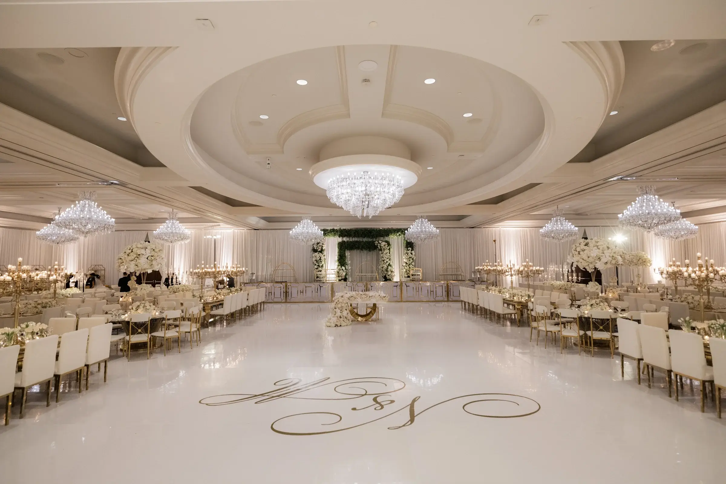 White ballroom with a gold monogram dance floor under crystal chandeliers at the Four Seasons Hotel Westlake Village