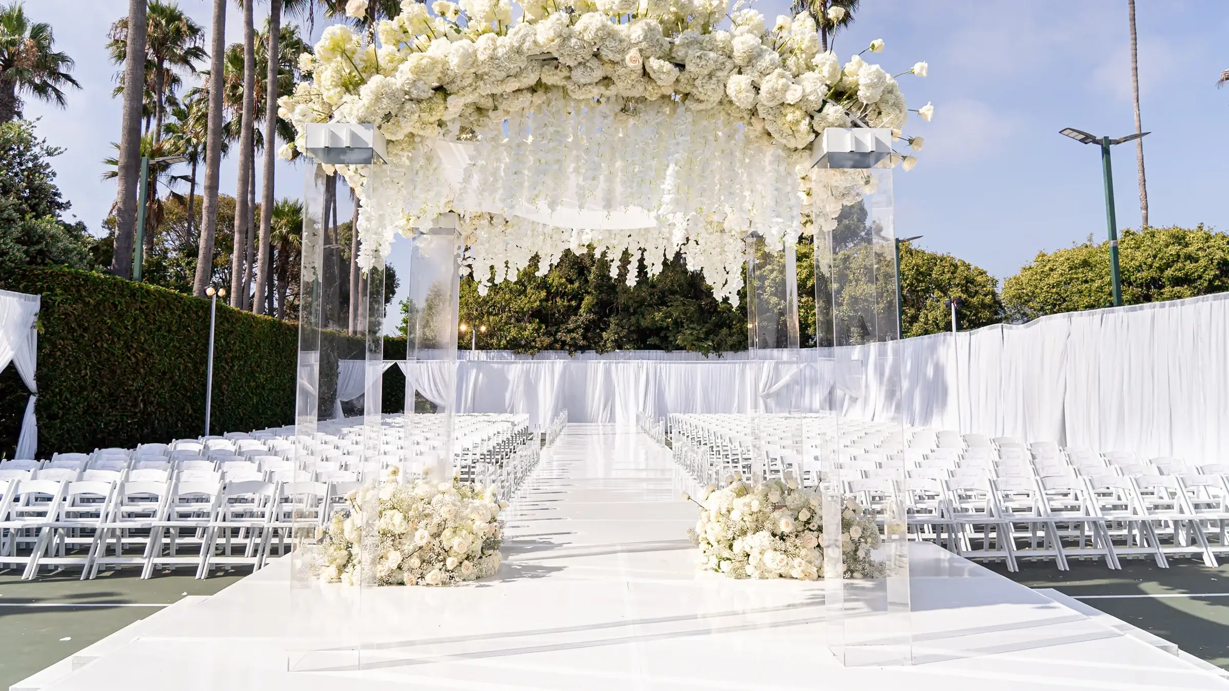 Outdoor Jewish wedding ceremony set with a white floral chuppah canopy and palm trees at The Ritz-Carlton, Marina del Rey