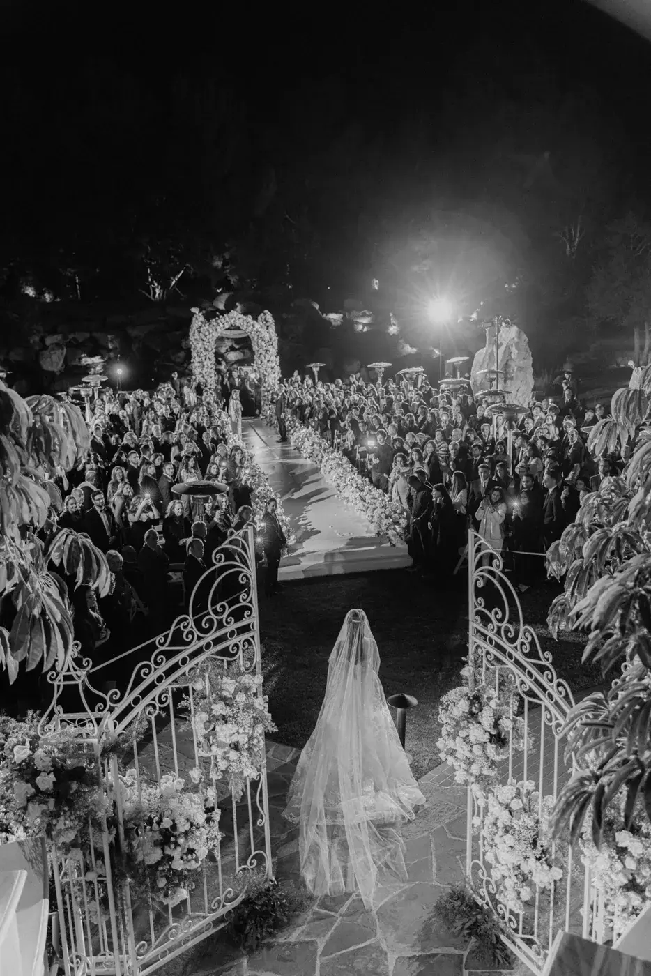 Black-and-white view down the floral ceremony aisle at night at the Four Seasons Hotel Westlake Village.