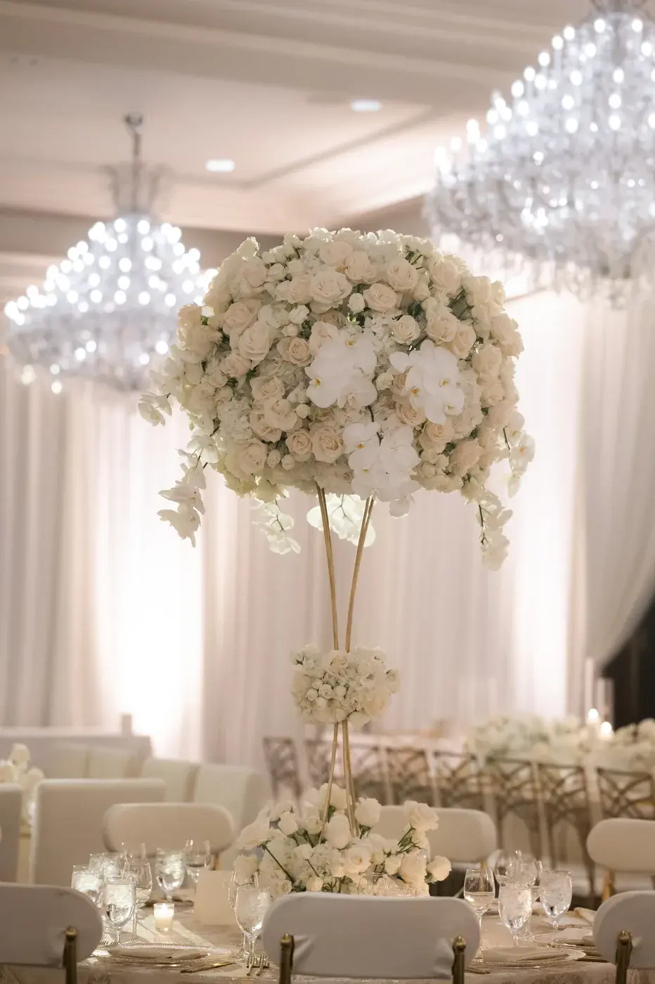 Elevated white rose centerpiece framed by chandeliers and draping at the Four Seasons Hotel Westlake Village.