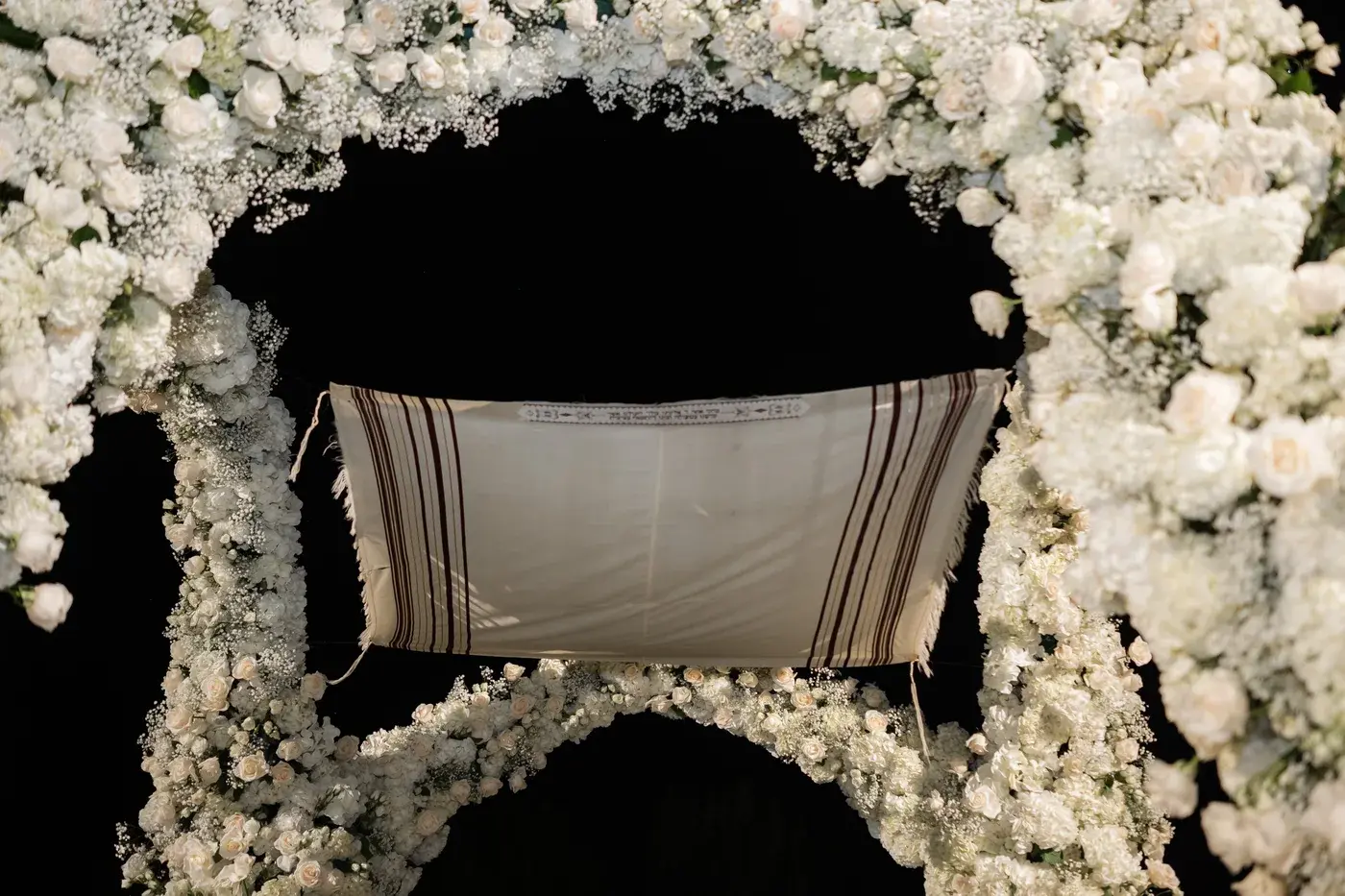 Tallit canopy inside the white floral chuppah at night at the Four Seasons Hotel Westlake Village.