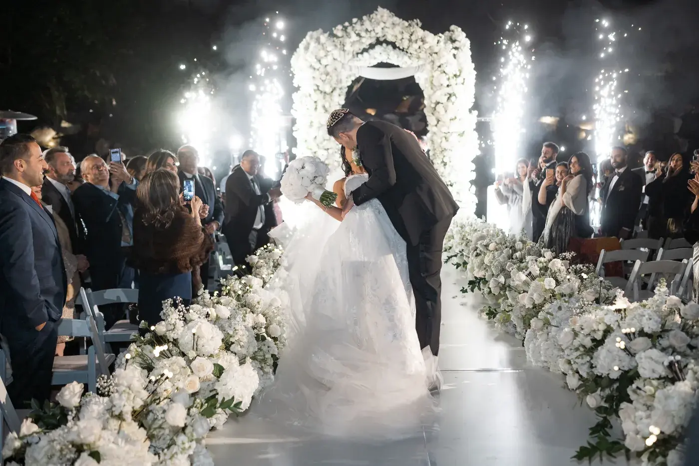 The couple kissing at the end of the aisle with cold spark fountains at the Four Seasons Hotel Westlake Village.