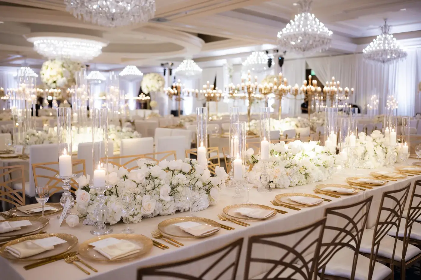 Long reception tables with gold chargers, candles and white florals at the Four Seasons Hotel Westlake Village.