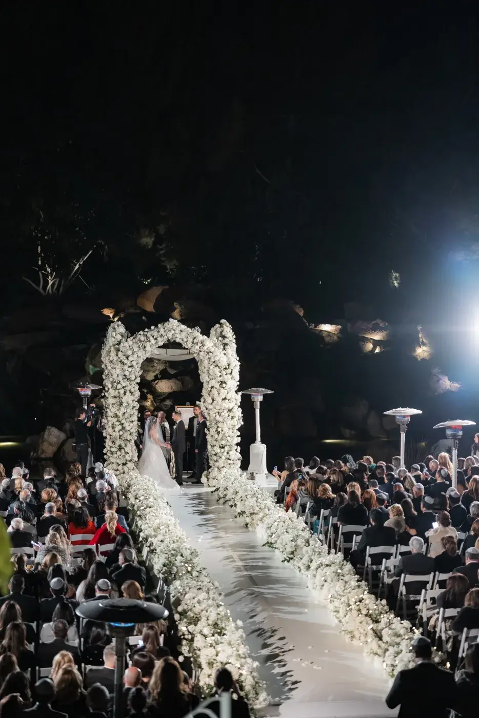 Evening ceremony under the floral chuppah with guests seated at the Four Seasons Hotel Westlake Village.