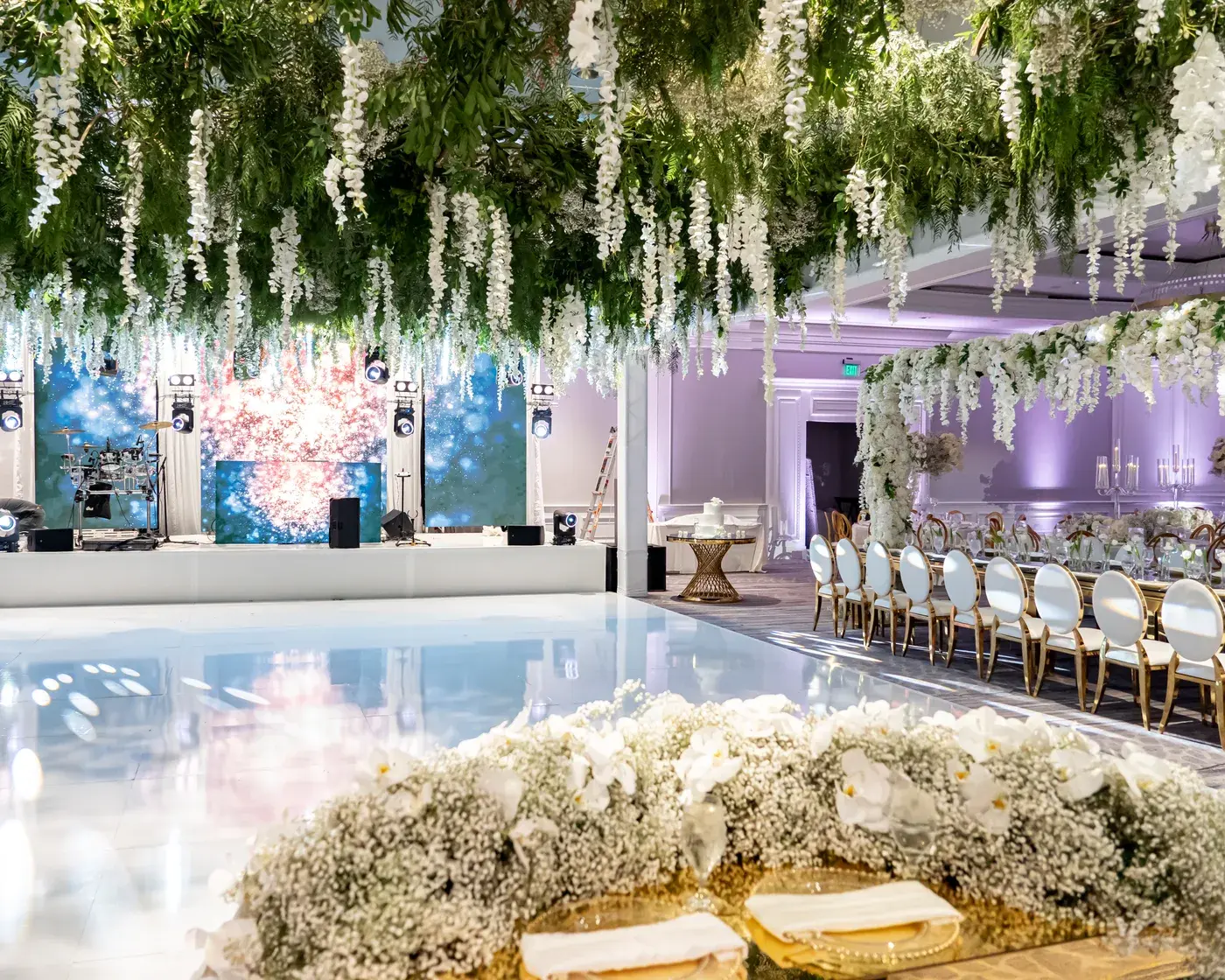 Wedding reception with LED walls, lavender uplighting and a hanging wisteria ceiling over a white dance floor at The Ritz-Carlton, Marina del Rey.