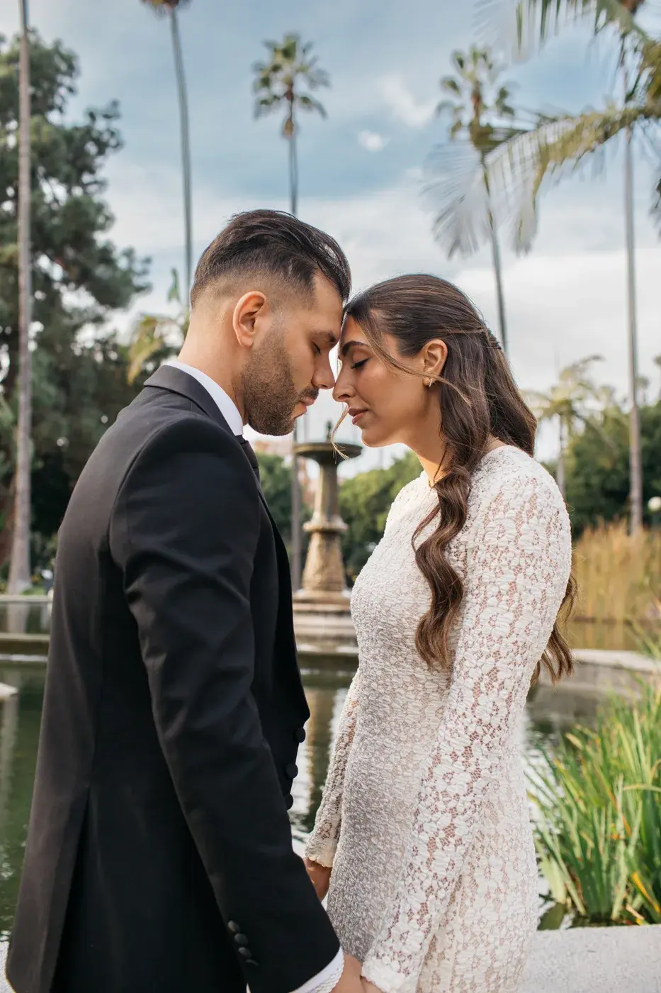 Couple portrait beside a garden fountain and palm trees at The Ritz-Carlton, Marina del Rey.
