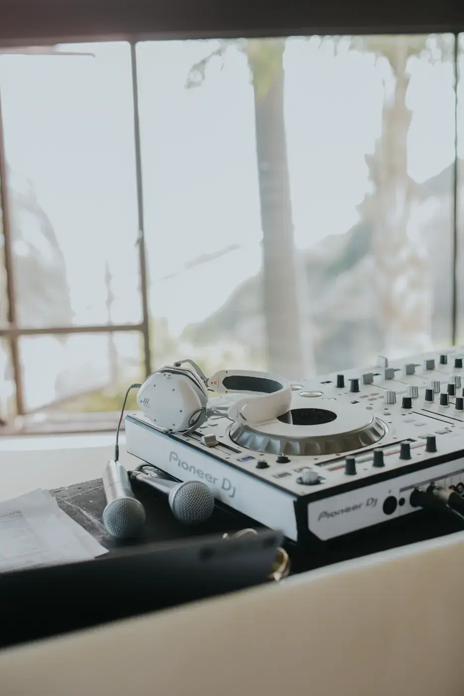 A DJ controller set up at the booth at the Bel-Air Bay Club, with the ocean visible through the window behind it.