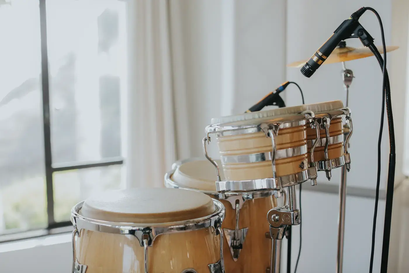 Conga drums on stands with microphones positioned over them, beside a window at the Bel-Air Bay Club.