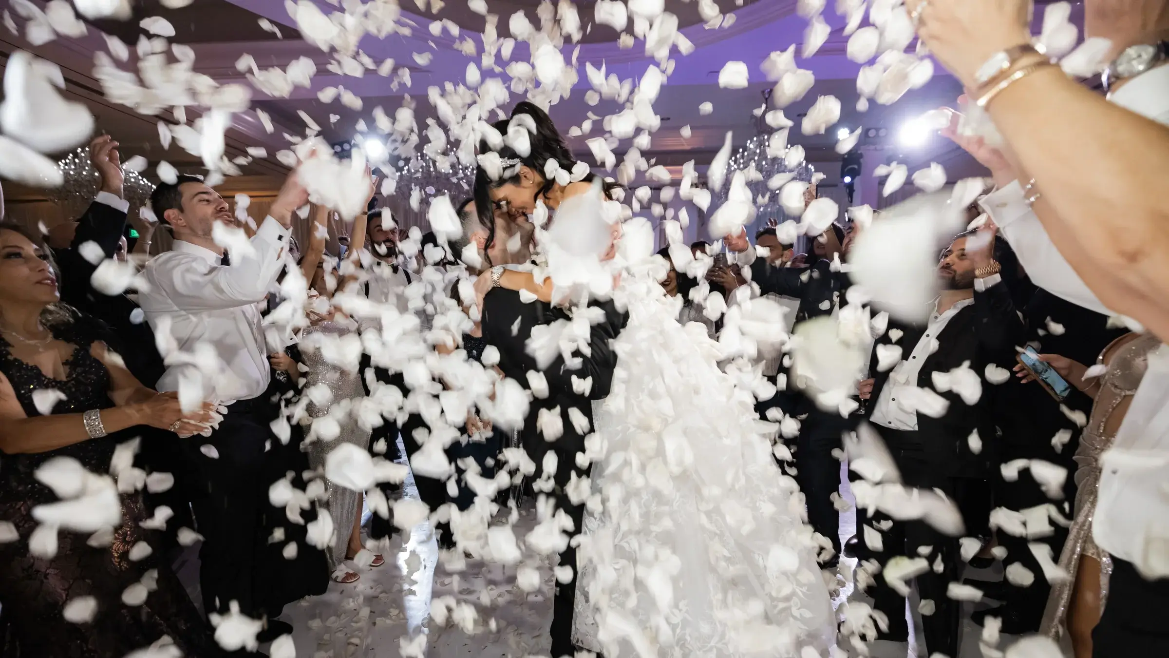 Couple celebrating on a packed dance floor as white petals fall at the Four Seasons Hotel Westlake Village