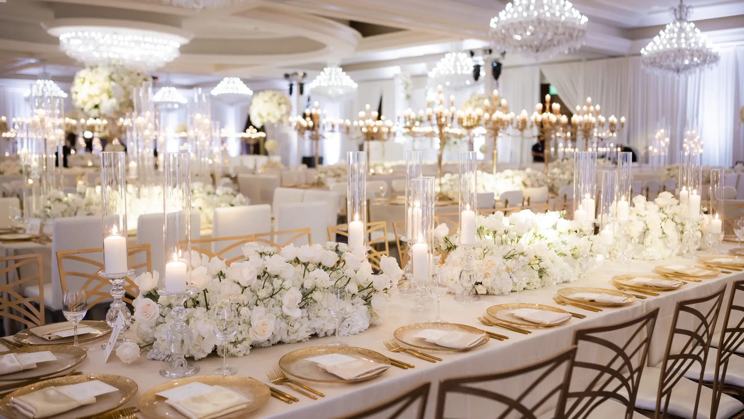 Long reception tables with gold chargers, candles and white florals at the Four Seasons Hotel Westlake Village