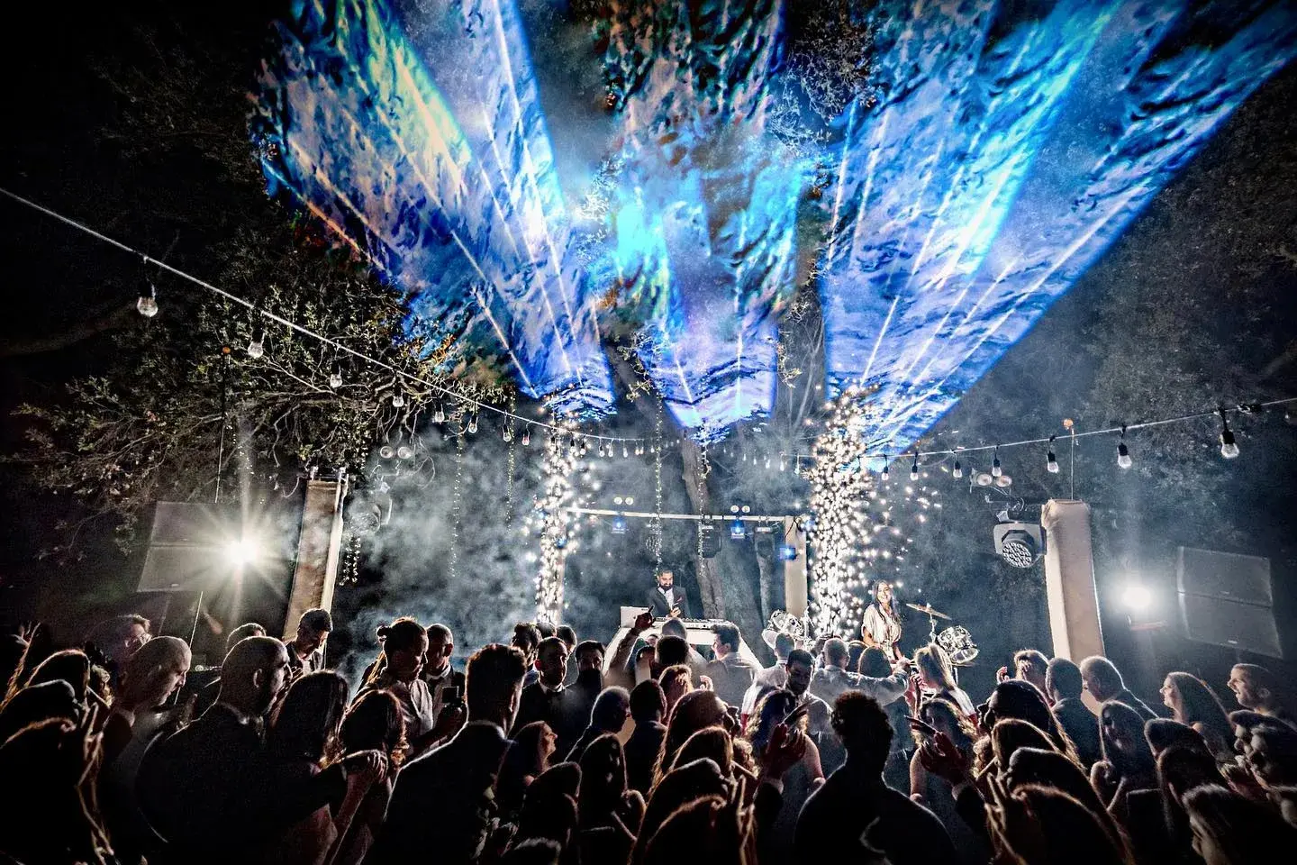 Concert-style beam lighting and cold spark effects over a packed dance floor