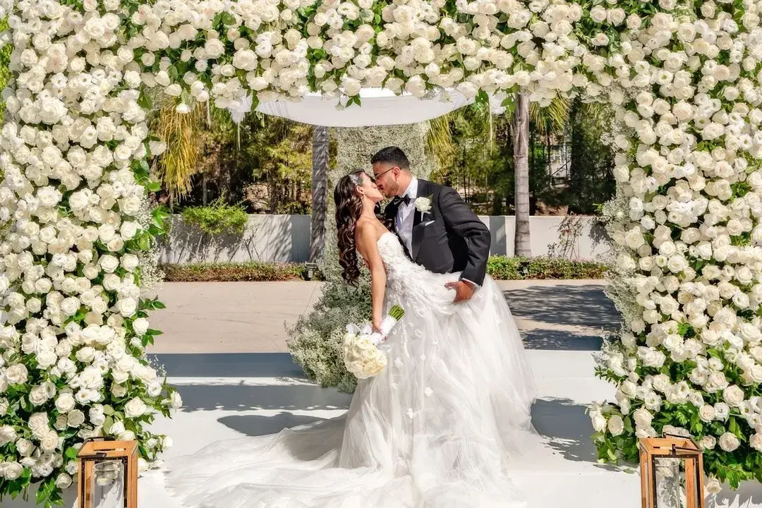 Bride and groom beneath a white floral chuppah at an outdoor wedding ceremony in Los Angeles