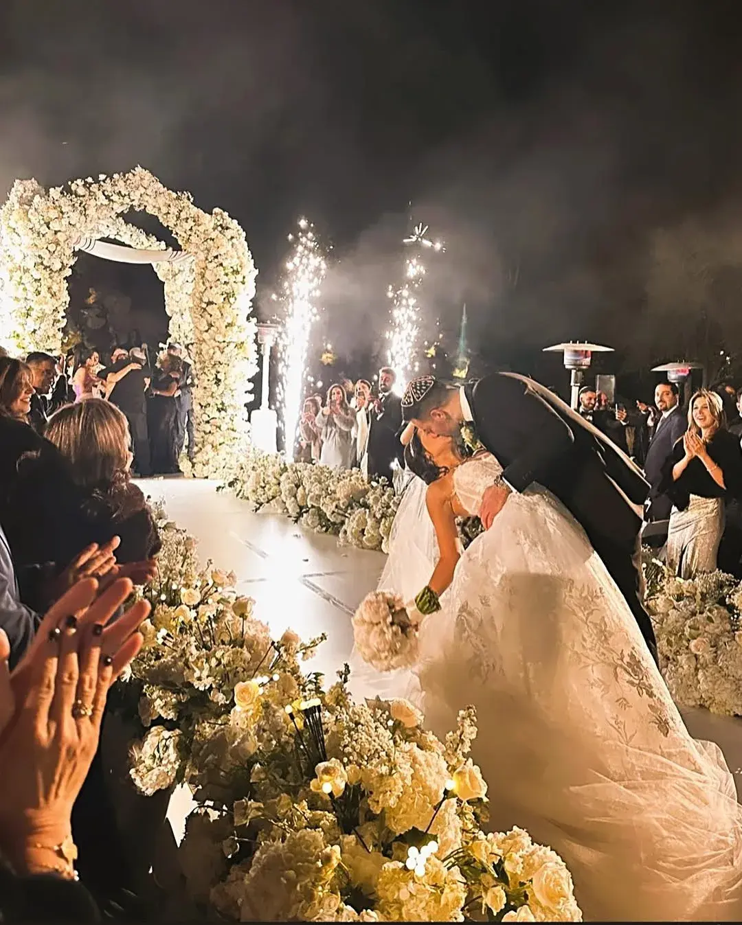 Bride and groom kissing at a night floral ceremony with cold-spark effects at a Los Angeles wedding