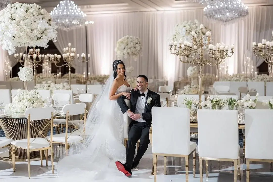 A luxury wedding ballroom with lush white florals, gold candelabras, and elegant tablescape décor at a Los Angeles event coordinated by NEXT LEVEL EVENTS
